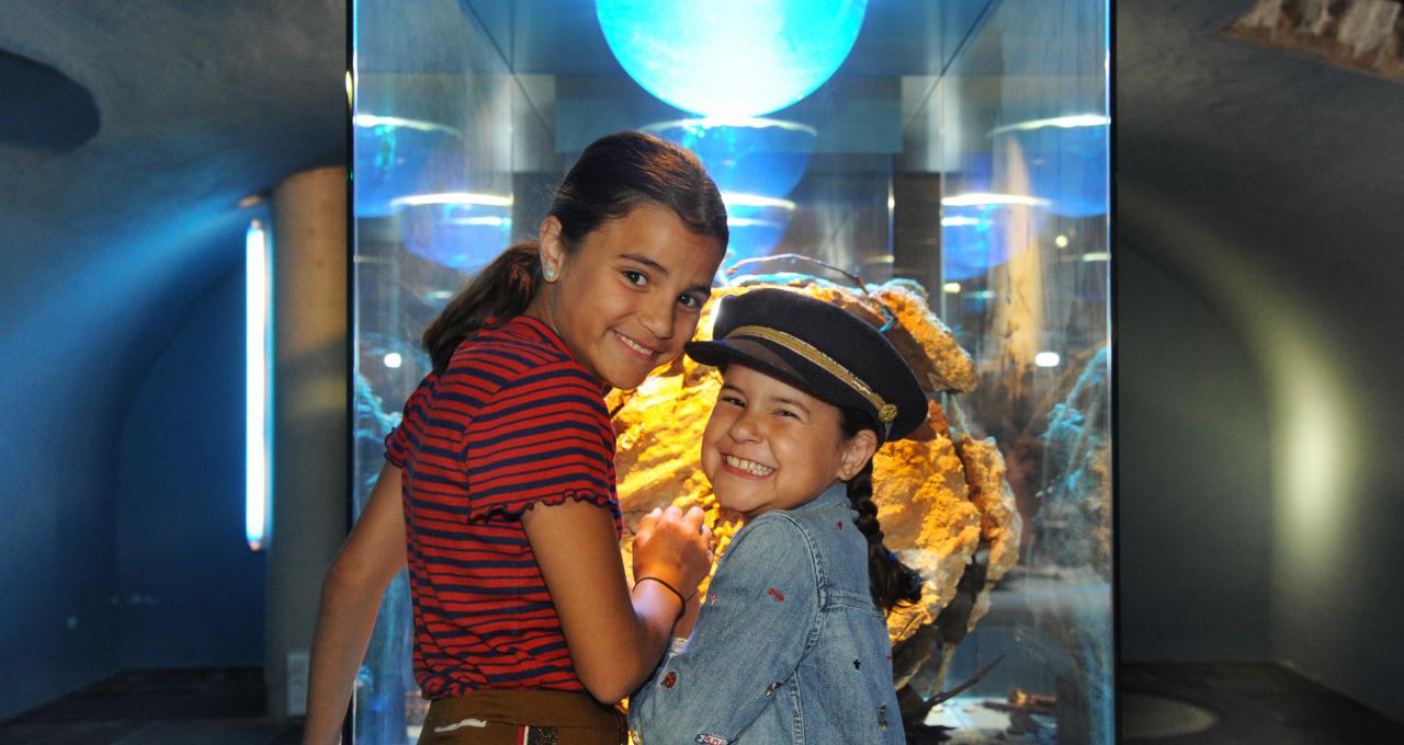 Twee lachende meisjes voor de vitrine onderwaterarcheologie in het muZEEum