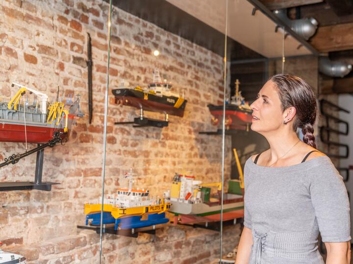 Vrouw bij vitrine met scheepsmodellen