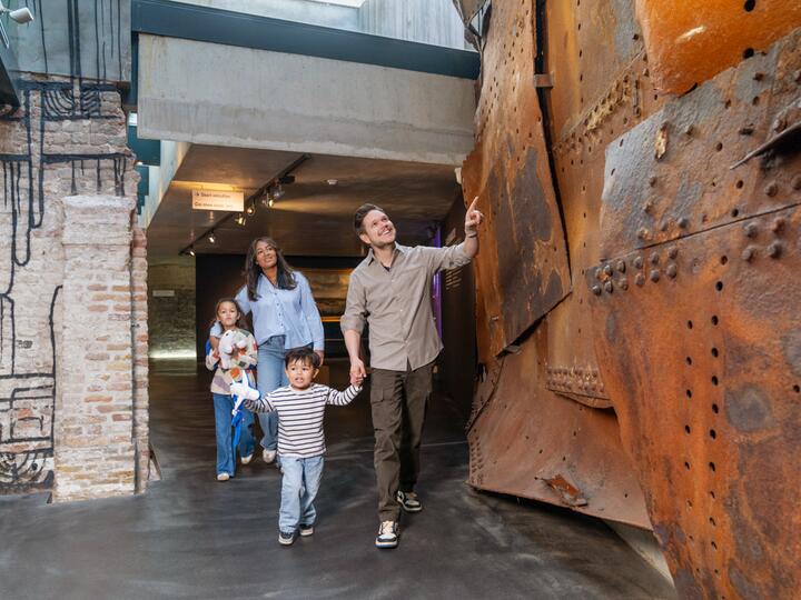 Gezin loopt in museum langs muur van scheepshuiden 